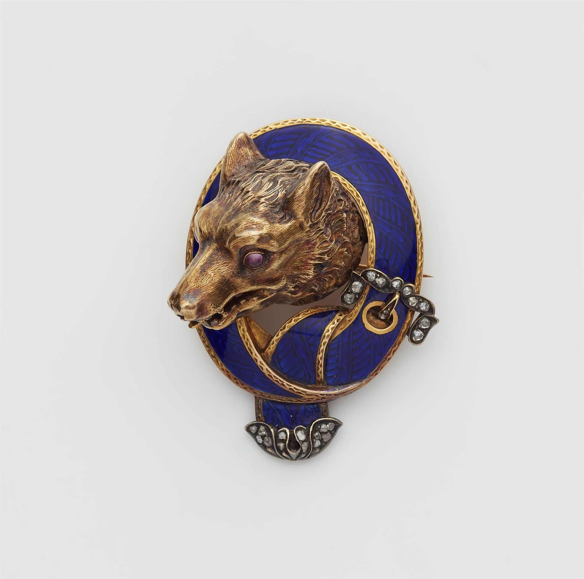 A Victorian 18k gold enamel ruby and diamond hunting brooch with head of a wolf.