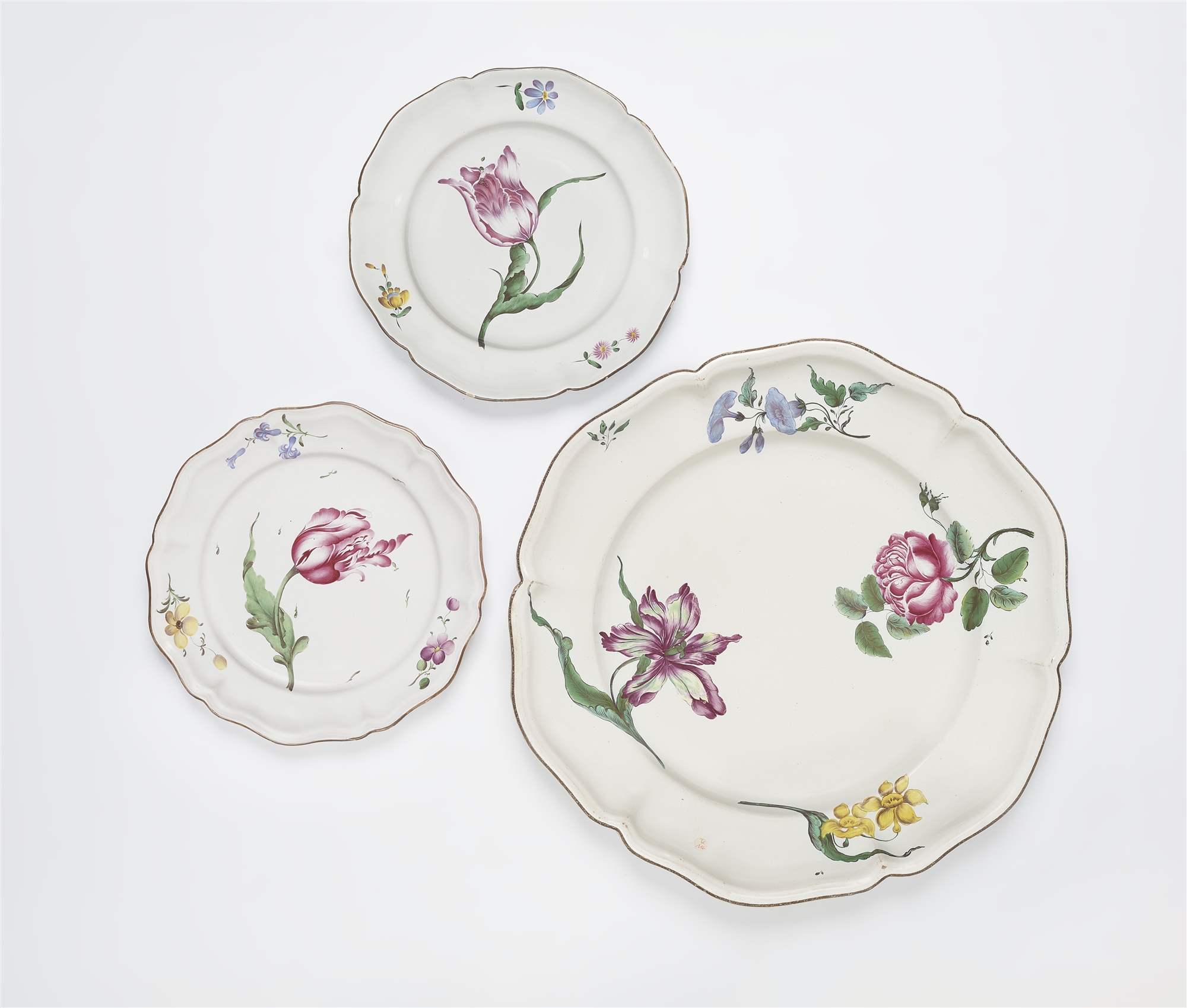 A round Strasbourg faience platter and two plates with 'fleurs esseulées'