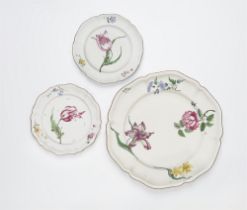 A round Strasbourg faience platter and two plates with 'fleurs esseulées'