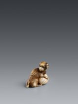 An ivory netsuke of a dog with a ball. Around 1800