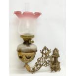 A Victorian ornate brass wall handing double burner oil lamp with later shade. 36x54cm