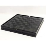 A glass top games board with chess, draught and domino pieces.