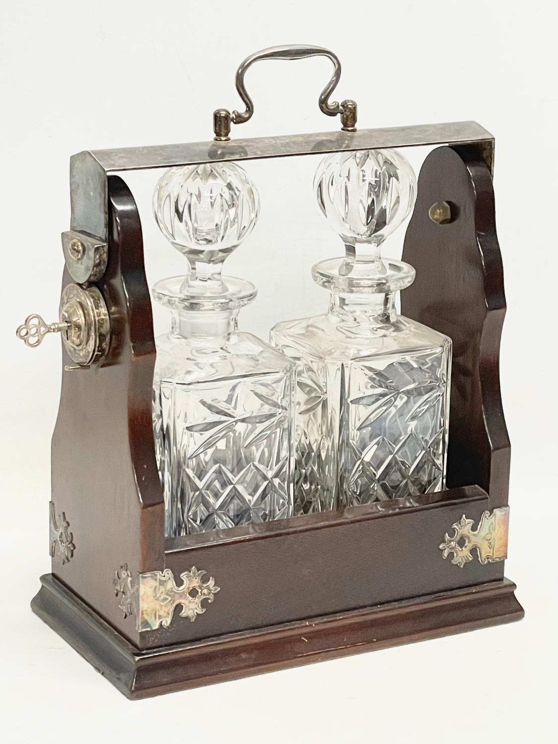 A vintage mahogany and silver plated tantalus with a pair of crystal decanters. 25x13x31cm