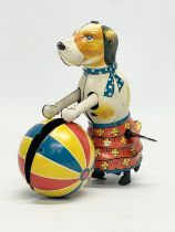 A vintage tinplate windup dog with ball. 11x11cm