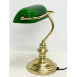A brass desk lamp with glass shade.