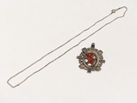 An ornate silver pendant with silver necklace.