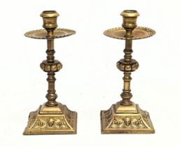 A pair of 19th century ornate brass candlesticks with ram head decoration. 23cm