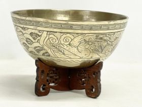 A large early 20th century Chinese brass bowl on wooden stand. Bowl measures 24x11cm.