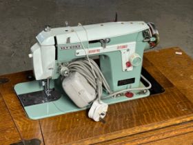 A vintage oak Singer table with New Home sewing machine. 87x41x78cm