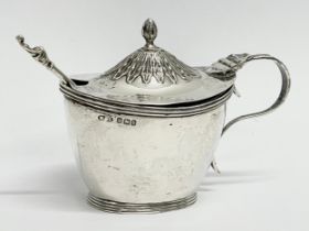 A silver mustard pot and spoon. 77.18 grams.
