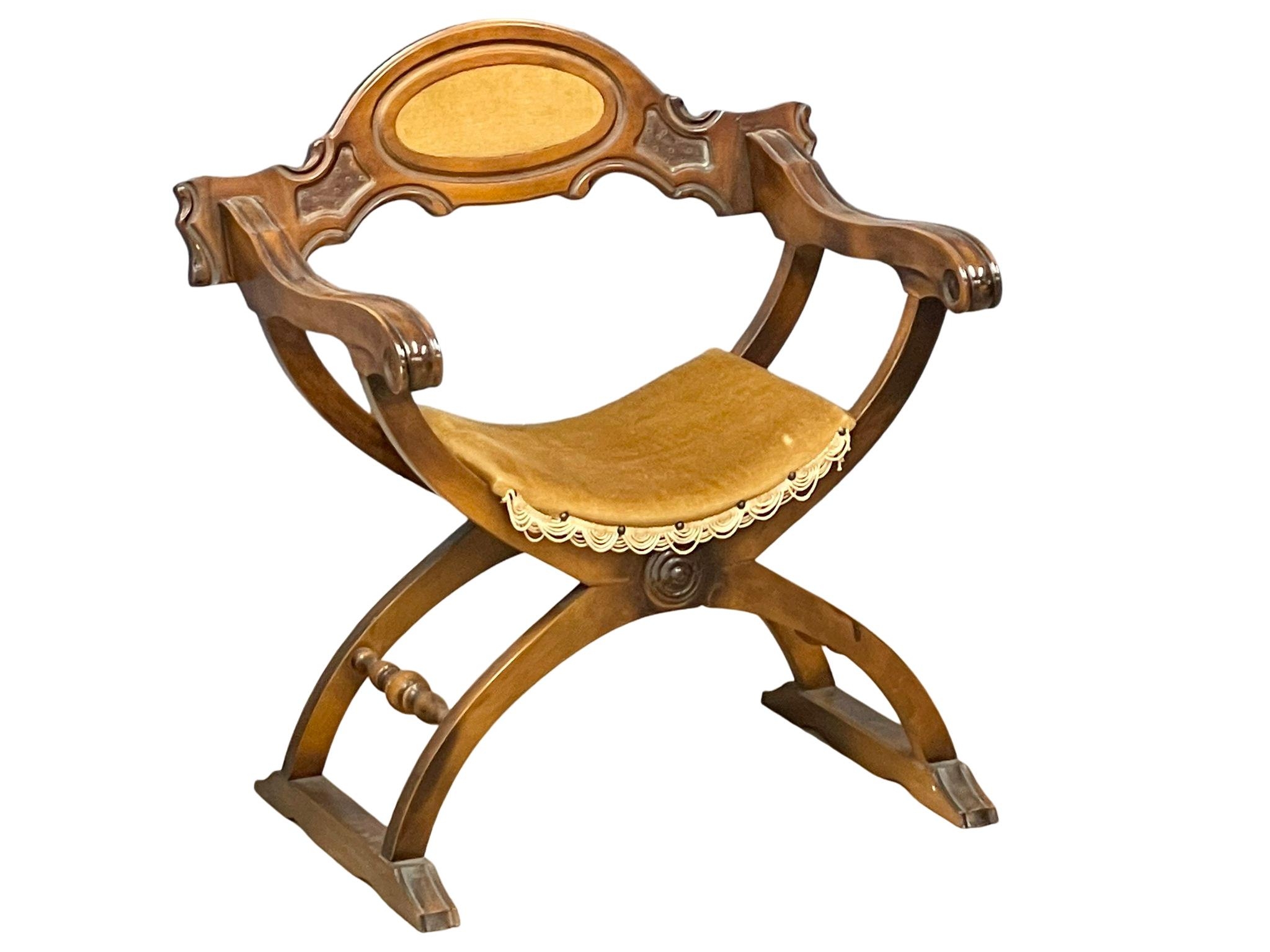 a 19th century style carved x-framed armchair.
