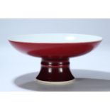 A ruby-red glazed high-footed large porcelain plate, with a raised string pattern on the foot, and