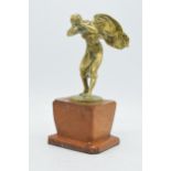 Vintage cast brass figure of a lady with clothes flailing in the wind, mounted onto a wooden base,