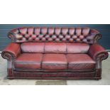 Red oxblood leather chesterfield-style three seater sofa with button-back design and metal
