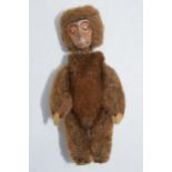 A 1930s/ 1940s miniature Schuco monkey, mohair body, painted tin-plate face and articulated limbs.