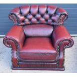 Red oxblood leather Chesterfield-style button-back armchair with metal beading, 110x96x92cm tall. In