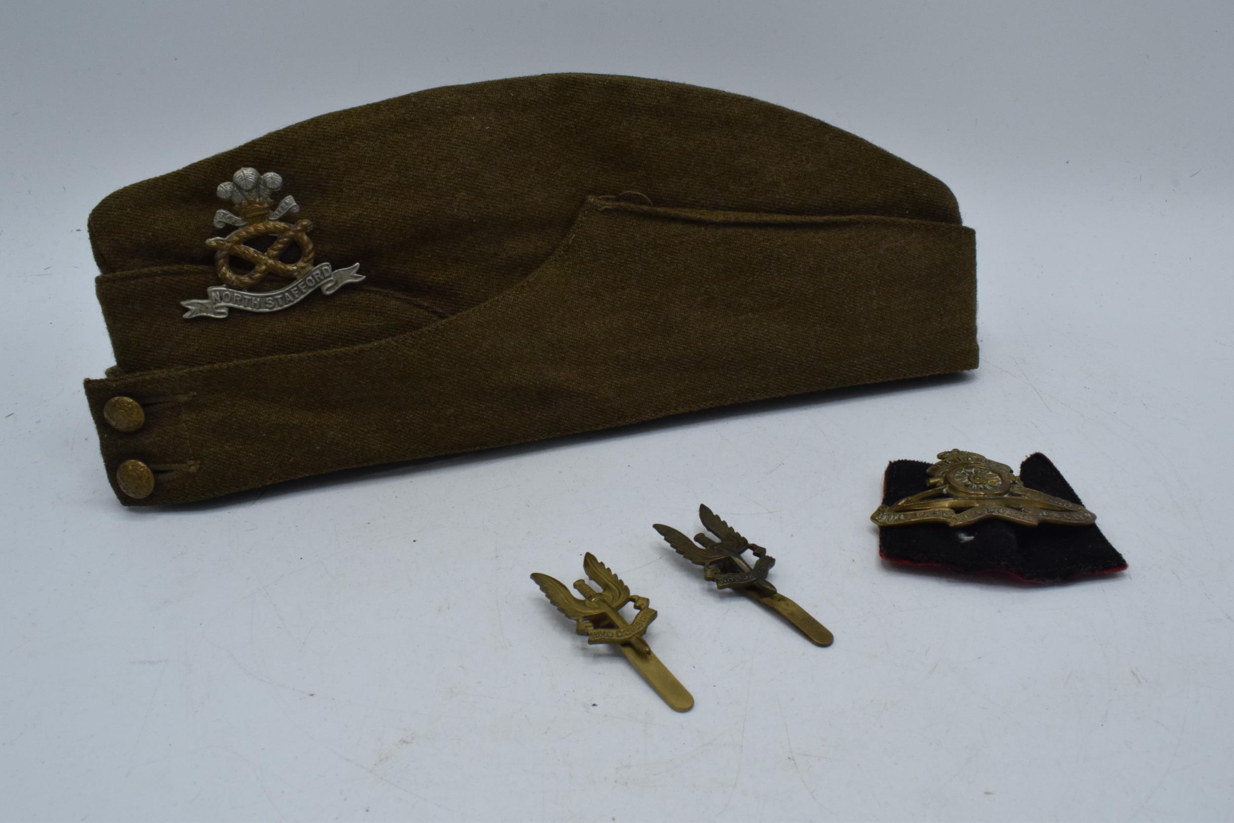 A Staffordshire regiment military cap. Two SAS regiment cap badges and a Royal Artillery Cap