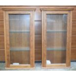 A pair of 20th century oak wall mounted display cabinets with glazed doors, each with 2 glass