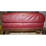 Red leather foot stool with wooden base, 84x60x44cm tall.