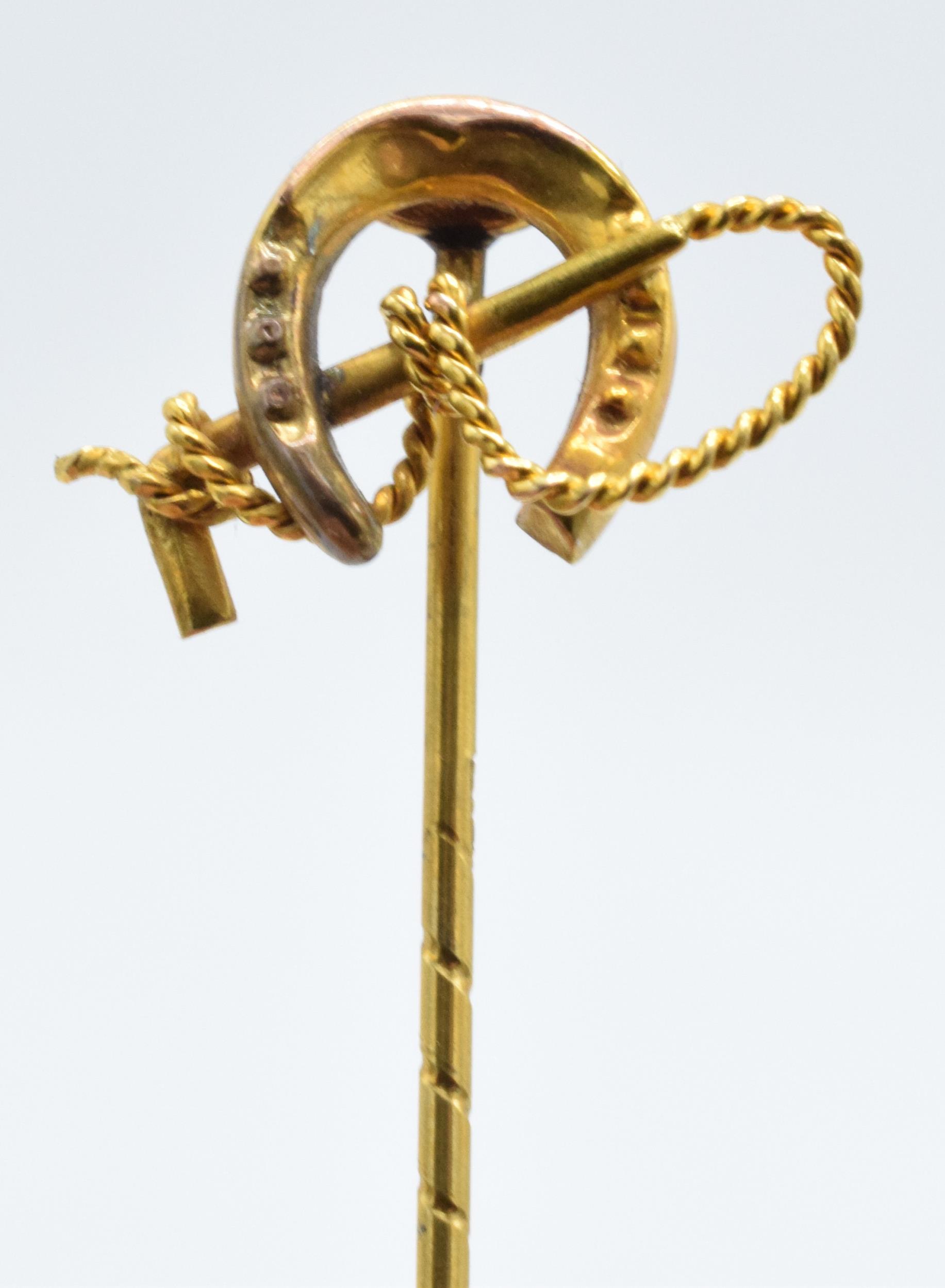 9ct gold stick pin in the form of a riding crop and horseshoe, 1.3 grams, 5cm long.