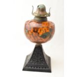 Edwardian oil lamp with ornate metal base and painted glass reservoir, 29cm tall. Crack to the