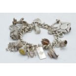 A heavy silver charm bracelet with varying charms to include a swivel fob, a windmill, a magic
