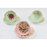 A trio of Paragon cups and saucers to include a green coloured duo with pink rose decoration to