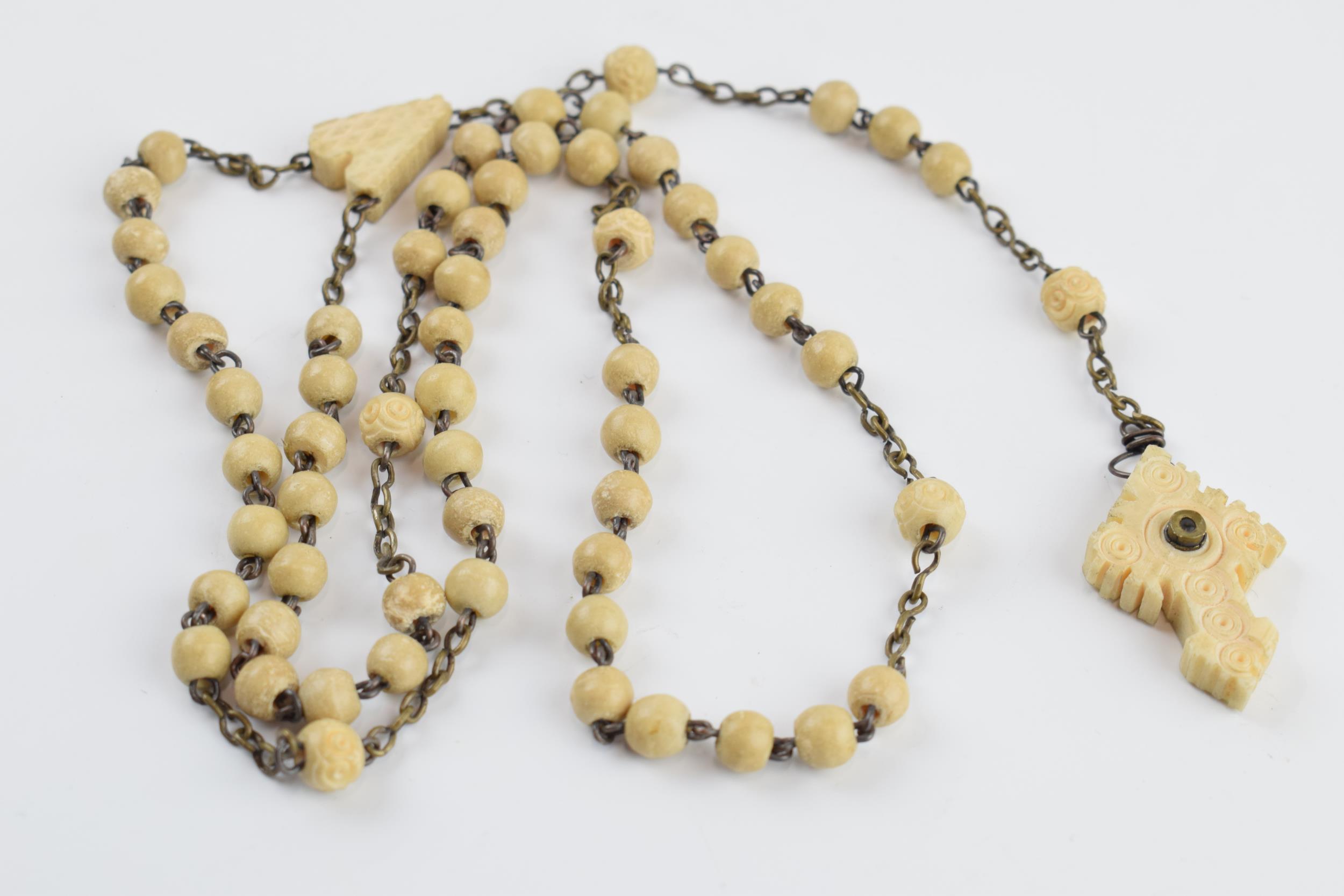 A set of bone rosary beads with cross stanhope with village scenes, 52cm long.