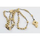 A set of bone rosary beads with cross stanhope with village scenes, 52cm long.