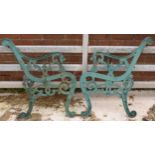 A pair of vintage heavy cast iron bench ends in painted green decoration, 77cm tall (2).