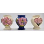 A trio of Moorcroft vases. Two with cream ground with floral design and one in blue. Height 9.5cm.
