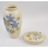 A Moorcroft vase in a floral pattern. Cream ground together with a similar lidded pot. Vase height
