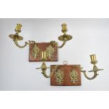 A pair of mid 20th century figural brass wall sconces mounted on wooden plaques (2), 34cm wide.