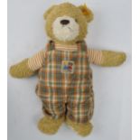 Steiff teddy bear wearing dungarees, 32cm long.