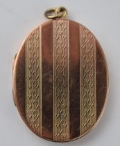 9ct gold large oval locket with striped decoration, Chester 1919, 9.9 grams total weight.