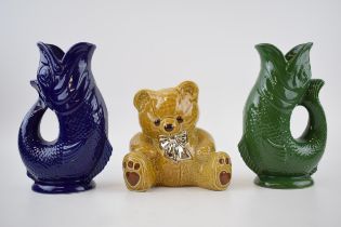 A trio of Wade Ceramics to include 2 Gluggle jugs in green and blue, 22cm tall, with a teddy bear