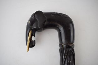 An ebony walking stick with carved elephant head handle and spirally turned design to shaft.