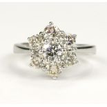 White gold (tests 18ct) diamond daisy cluster ring, seven round brilliant cuts, principle diamond