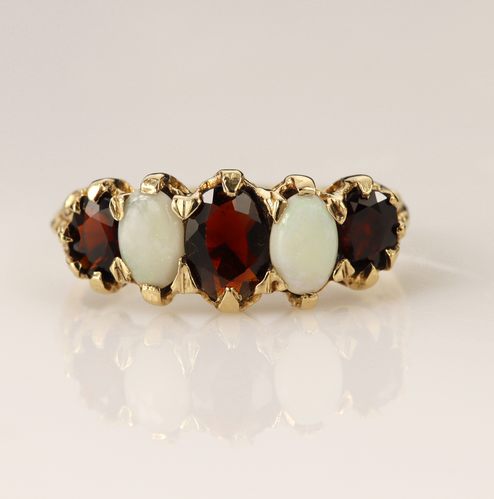 9ct yellow gold garnet and opal five stone boat shaped ring, three graduating oval mix cut garnets