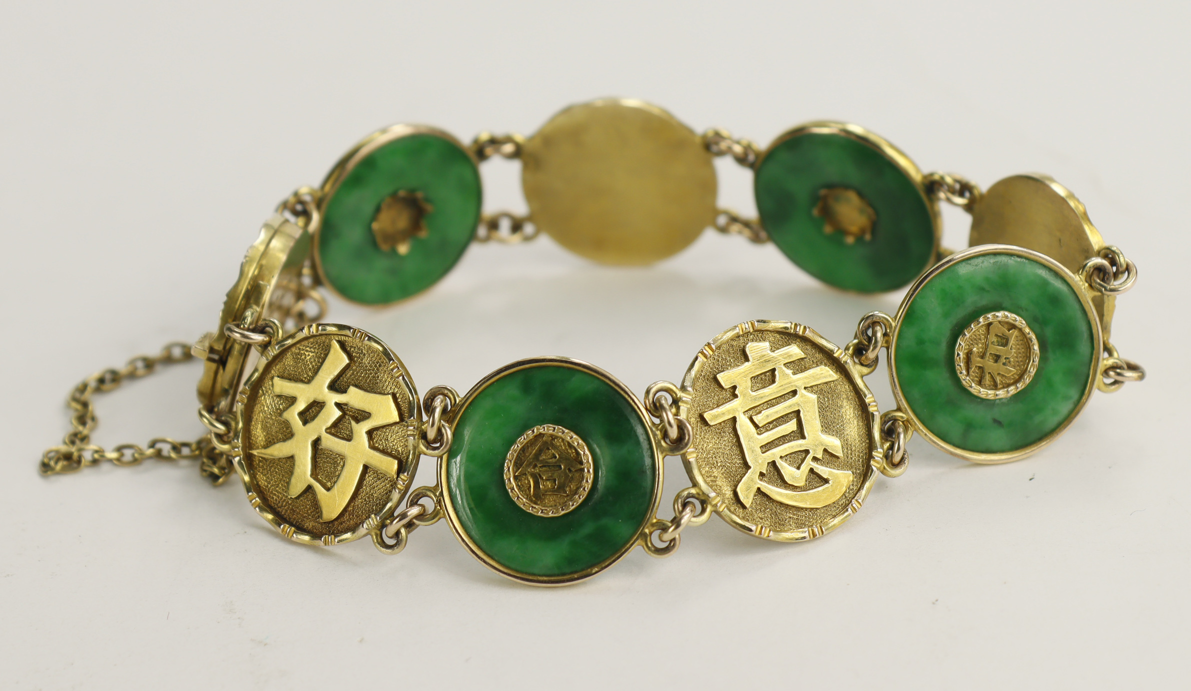 Yellow gold (tests 14ct) vintage jade bracelet, four circular jade discs with a gold bezel with