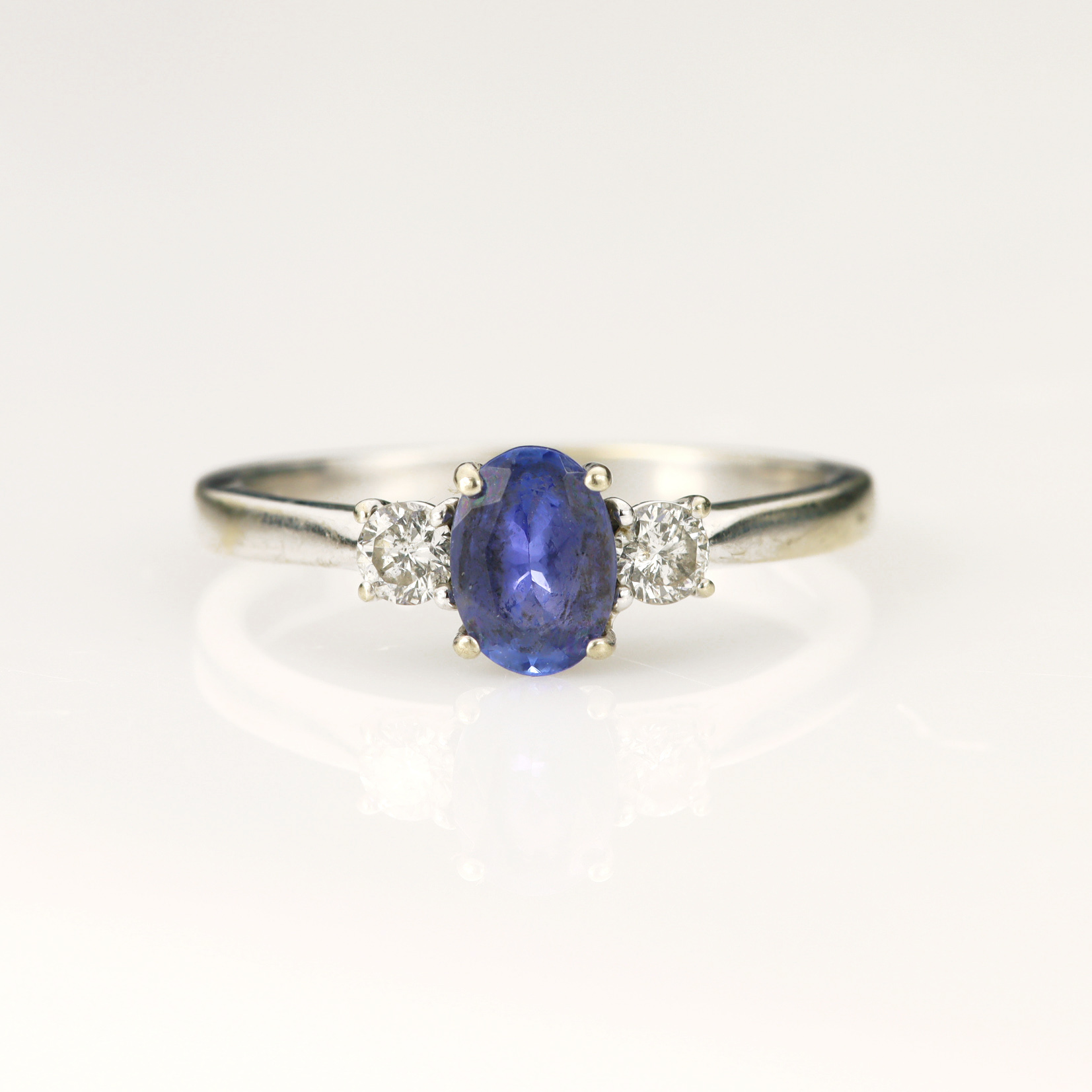 White gold (tests 9ct) tanzanite and diamond trilogy ring, one oval mixed cut tanzanite measuring