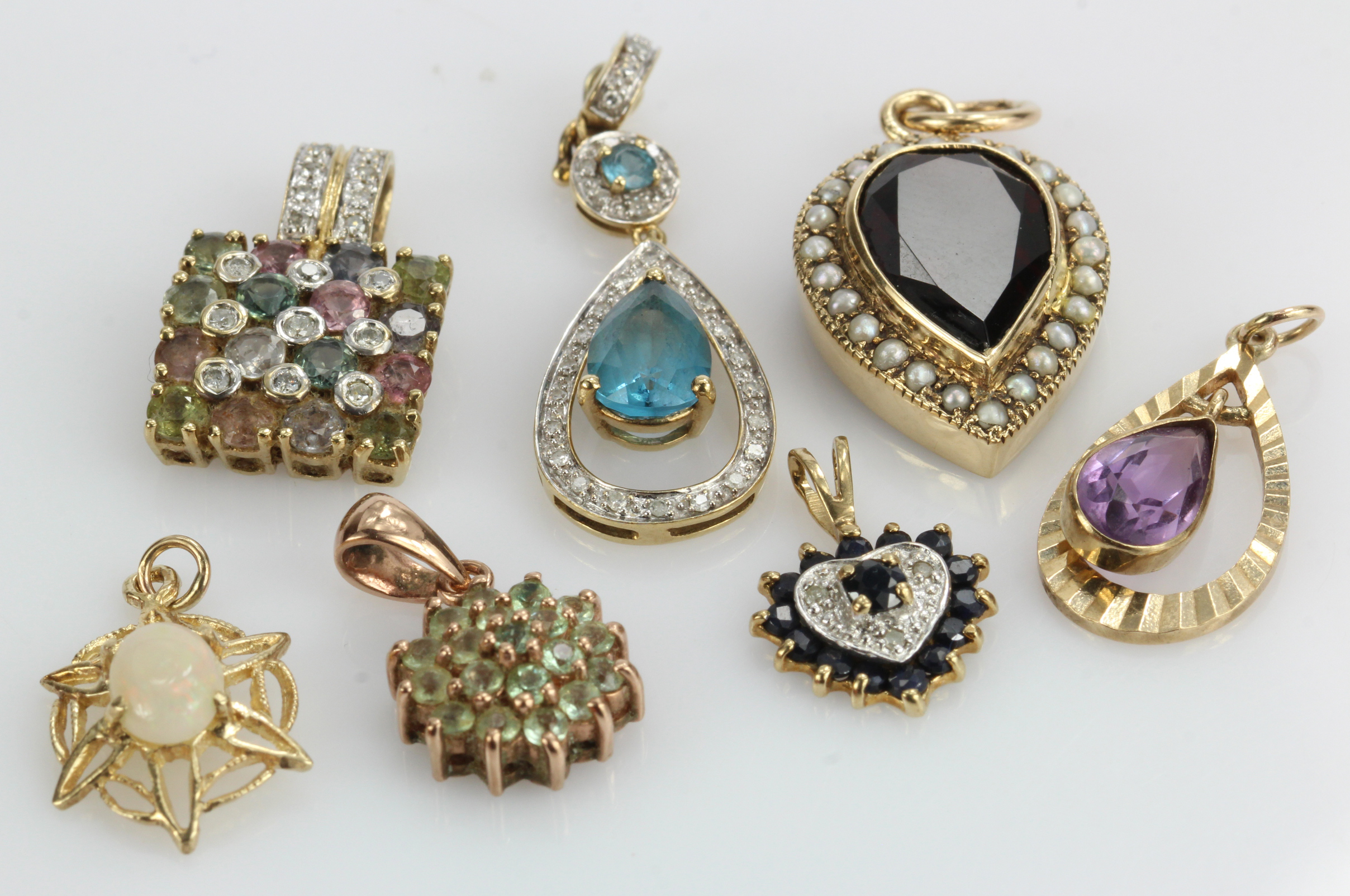 Assortment of 9ct gold pendants, some stones include diamonds, sapphires, opal, garnets, amethyst,