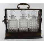 Tantalus. Three decanter tantalus, key present (stuck in the locked position), height 31cm, length