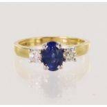 18ct yellow gold diamond and sapphire trilogy ring, oval mid-blue sapphire measures 7.3mm x 5.1mm
