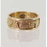 Tri-colour gold (tests 14ct) grape vine ring, yellow gold 7.2mm wide band decorated with rose and