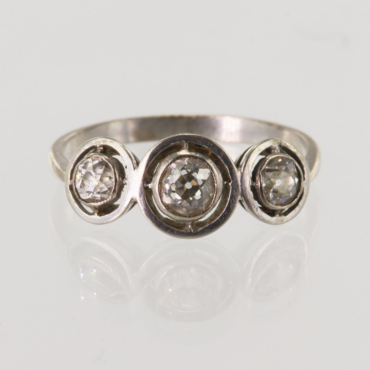 White metal diamond trilogy ring, set with three graduated round old cut diamonds calculated as