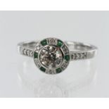 White gold (tests 18ct) diamond and emerald target halo ring, principle round brilliant cut