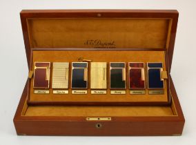 S. T. Dupont. A collection of seven S. T. Dupont lighters, contained in a Monday - Sunday Dupont