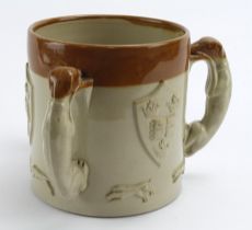 Glazed stoneware three handled cup, with hunting scene and Oxford University coat of arms to side,