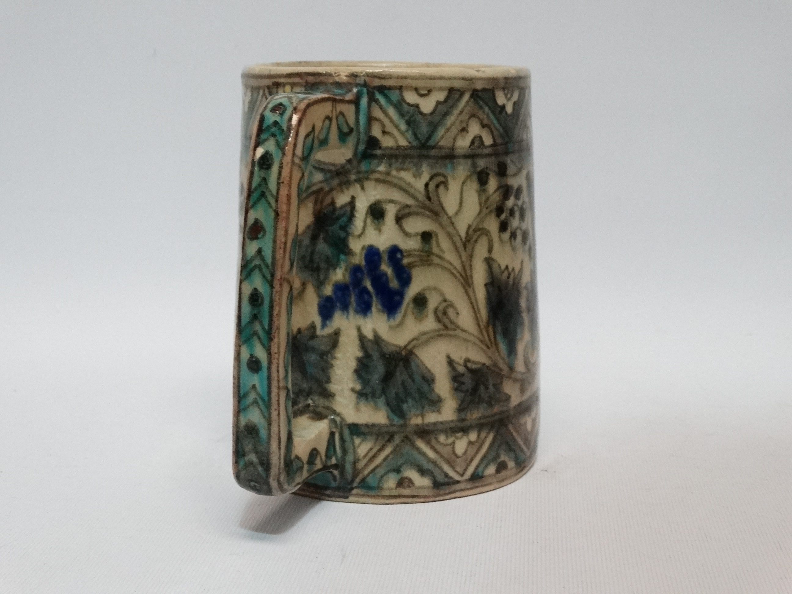 An Iznic glazed mug - decorated with vines within a geometric border, height 15cm. - Image 2 of 3